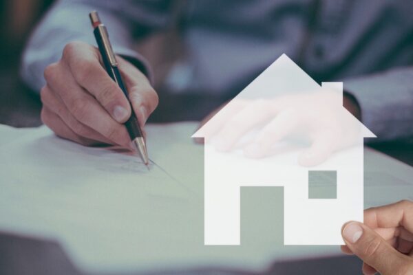 Persona firmando un informe de valoración junto a la silueta de una vivienda